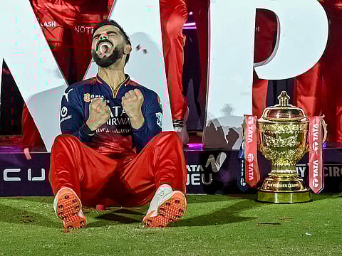 Royal Challengers Bengaluru's Virat Kohli reacts while sitting beside the trophy after winning the Indian Premier League (IPL) Twenty20 final cricket match against Punjab Kings at the Narendra Modi Stadium in Ahmedabad on June 4, 2025. 