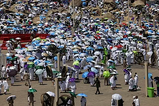 Muslim pilgrims holding umbrellas to protect themselves from the heat, walk around Saudi Arabia's Mount Arafat, also known as Jabal Al Rahma or Mount of Mercy, during the climax of the Hajj pilgrimage on June 5, 2025.