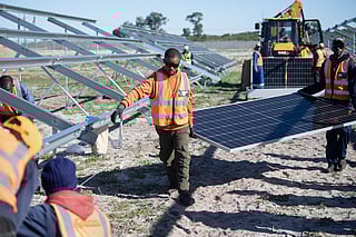 Workers carry solar panels to be fitted onto frames during construction at South Africa’s first municipally owned solar plant, during International World Environment Day, on June 05, 2025, in Atlantis, about 40km from Cape Town.