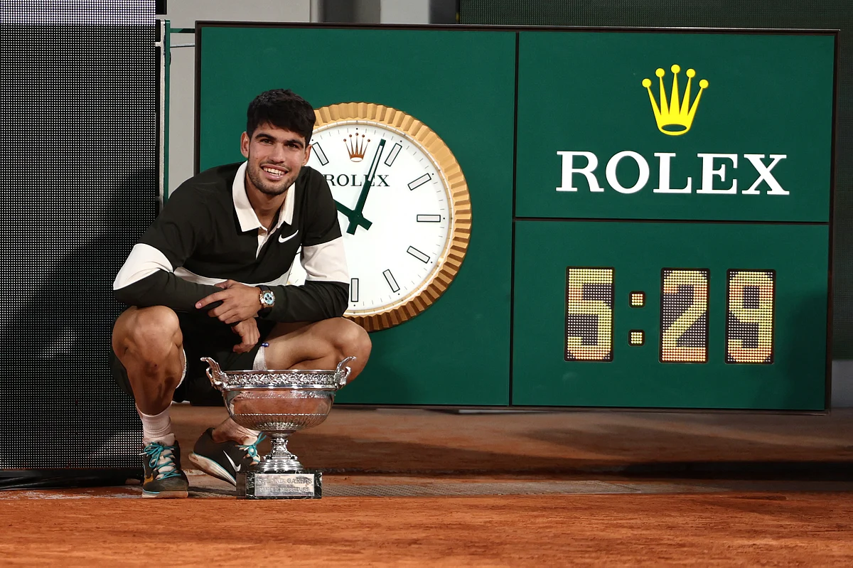 Spain's Carlos Alcaraz poses the trophy next to the clock that shows the duration of the match, the longest for a final in Roland-Garros, after winning against Italy's Jannik Sinner at the end of their men's singles final match on day 15 of the French Open tennis tournament on Court Philippe-Chatrier at the Roland-Garros Complex in Paris on June 8.