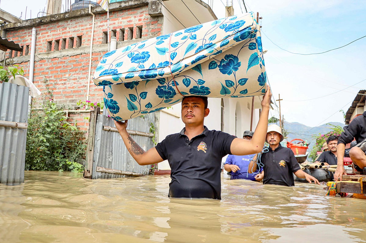 A man carries a mattress as he wades through floodwaters at Kongba in Imphal East on June 3, 2025. 