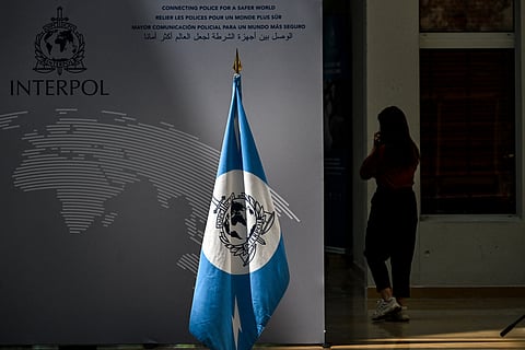 A woman walks near an Interpol flag ahead at the International Criminal Police Organisation Interpol headquarters in Lyon, eastern France, on June 9, 2025.