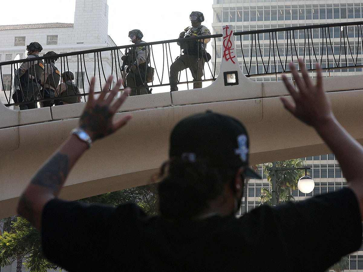 A protester raises his hands as police look down from a bridge in Los Angeles, California.