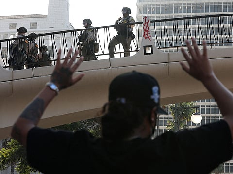 A protester raises his hands as police look down from a bridge in Los Angeles, California.
