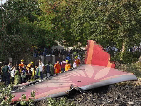 People stand around the debris of an airplane after it crashed in India's northwestern city of Ahmedabad in Gujarat state, on Thursday, June 12, 2025. 