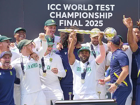 South Africa's captain Temba Bavuma holds the winner's trophy and celebrates with teammates after winning the World Test Championship, beating Australia at Lord's cricket ground in London, on June 14, 2025. 