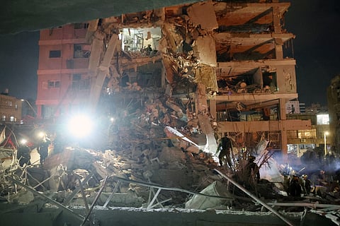 Responders work beside a damaged building following a hit by an Iranian ballistic missile in the Israeli city of Bat Yam, south of Tel Aviv, early on June 15, 2025.