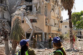 Israeli security forces gather outside a building that was hit by an Iranian missile in Israel's central city of Holon on June 19, 2025.