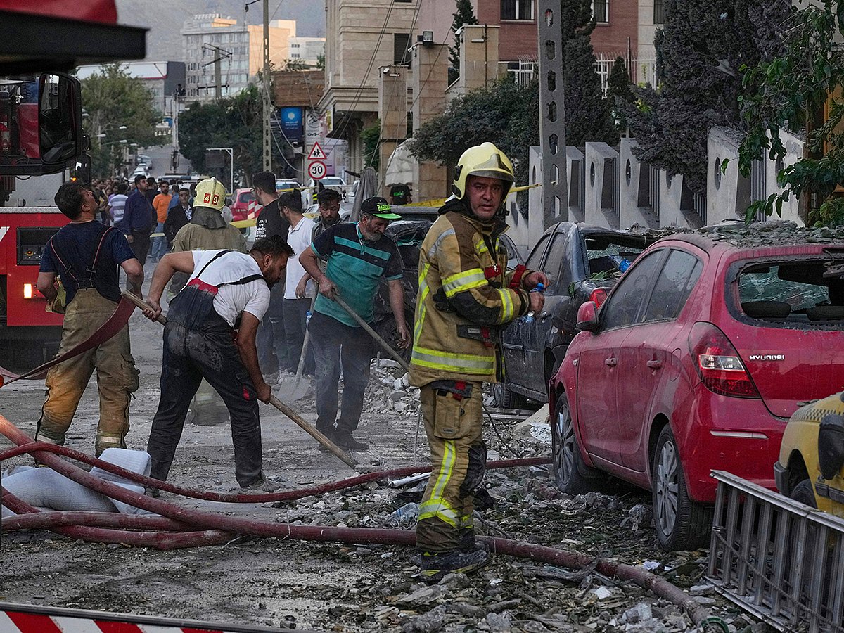 Firefighters and people clean up the scene of an explosion in a residence compound after Israel attacked Iran's capital Tehran, Friday, June 13, 2025. 