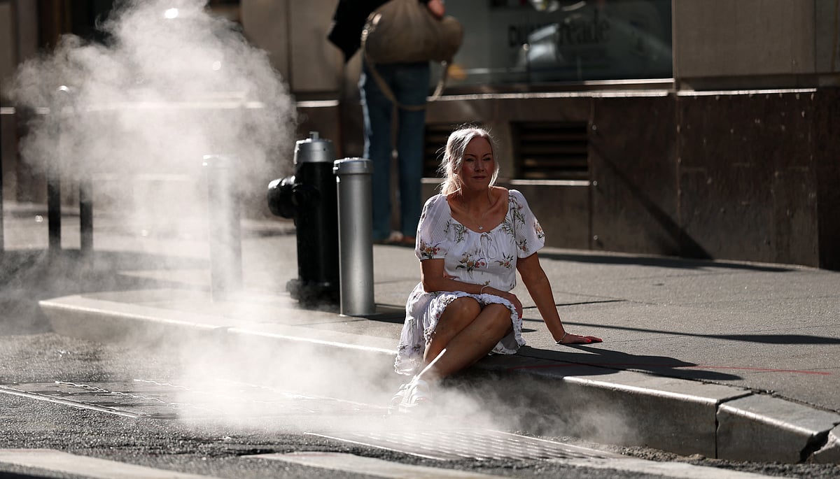 A tourist poses for pictures in steam grate on Wall Street June 23, 2025 as a excessive heat warning has been issued for NYC area.