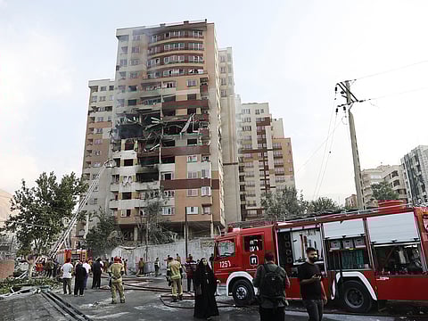 Firefighters work at the scene of a damaged building in the aftermath of Israeli strikes, in Tehran. 