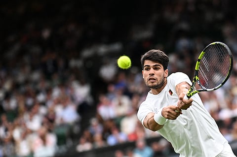 Spain's Carlos Alcaraz plays a backhand return to Russia's Andrey Rublev during their men's singles fourth round tennis match on the seventh day of the 2025 Wimbledon Championships at The All England Lawn Tennis and Croquet Club in Wimbledon, southwest London, on July 6, 2025.