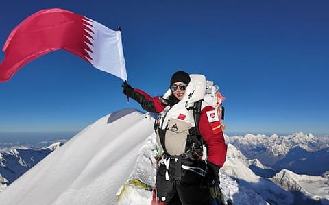 Elite mountaineer Sheikha Asma Al Thani raises her country's flag on Nanga Parbat peak.