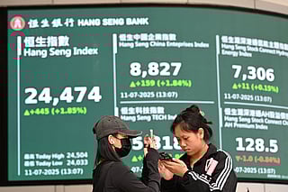Woman check their phones in front of an electronic sign board showing the the Hang Seng Index in Hong Kong. File photo taken on July 11, 2025.