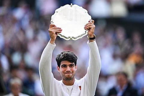 Spain's Carlos Alcaraz poses with the runner's up trophy, following his defeat against Italy's Jannik Sinner at the end of their men's singles final tennis match on the fourteenth day of the 2025 Wimbledon Championships at The All England Lawn Tennis and Croquet Club in Wimbledon, southwest London, on July 13, 2025.