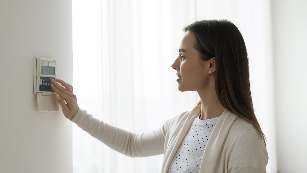 Young woman controlling air conditioning unit