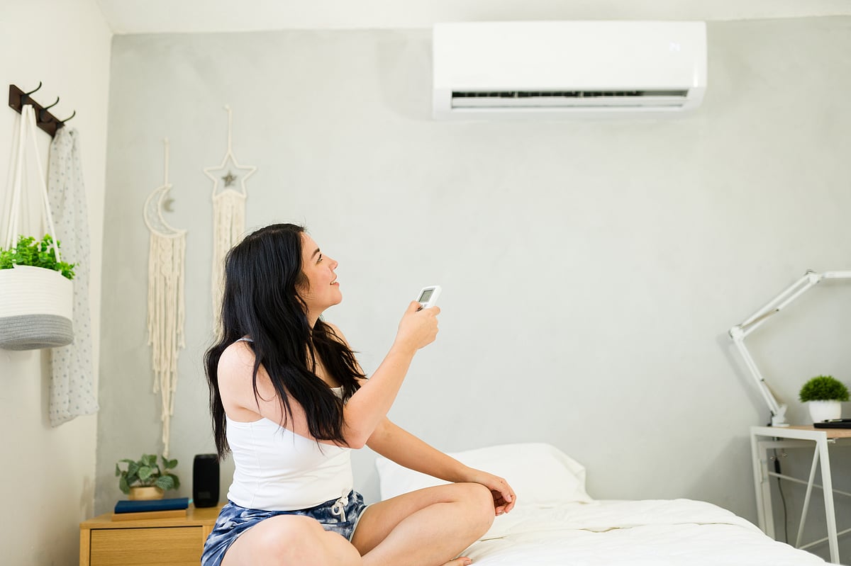 Young woman controlling air conditioning unit