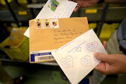 An employee shows letters - one of them bearing hand-drawn hearts on its back - addressed to the Pope at the Italian postal sorting centre in Fiumicino, near Rome.