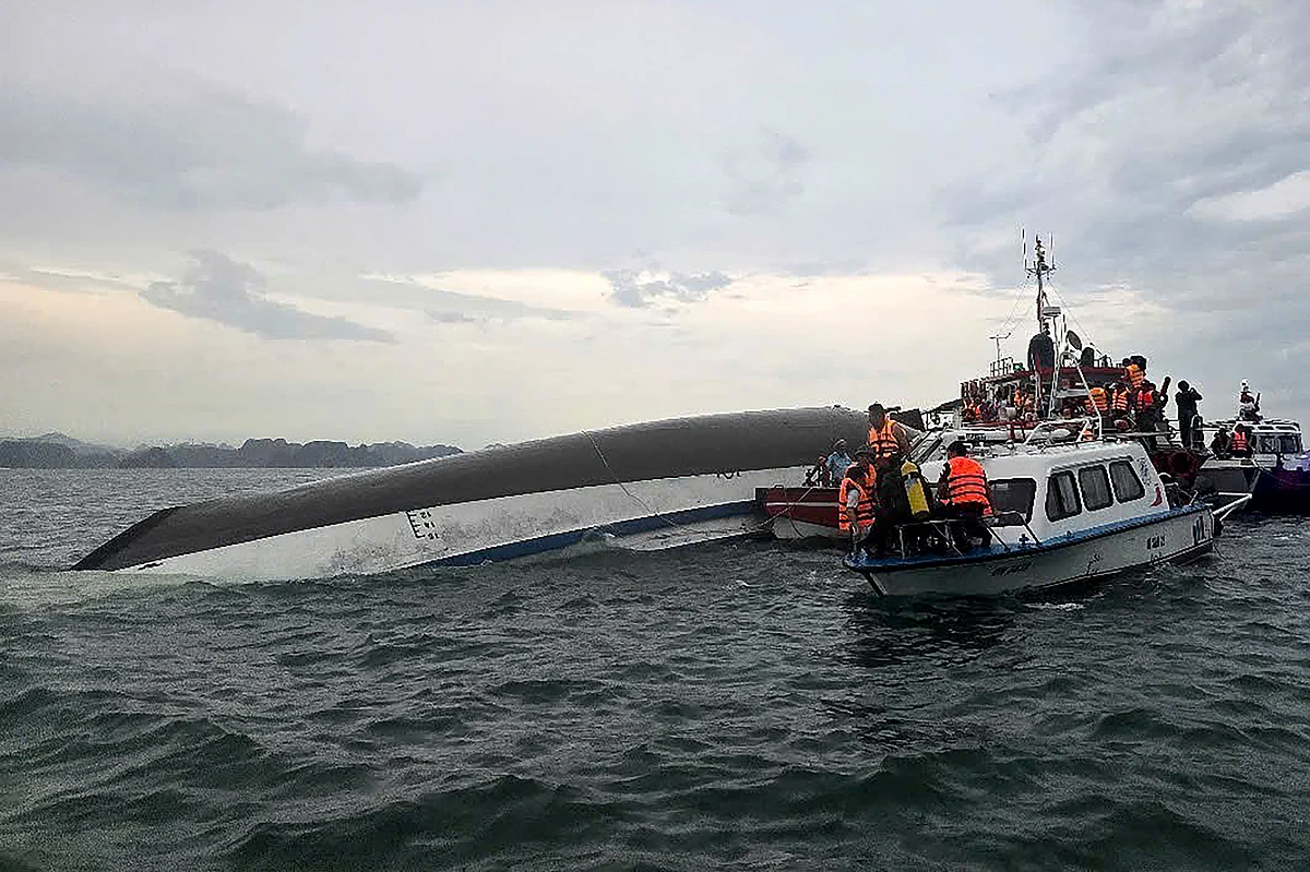 This handout photograph taken on July 19, 2025 and released by the Vietnam News Agency (VNA) shows relief personnel gathered around a capsized tourist boat (L) during a search and rescue operation in the Ha Long Bay, Quang Ninh province.