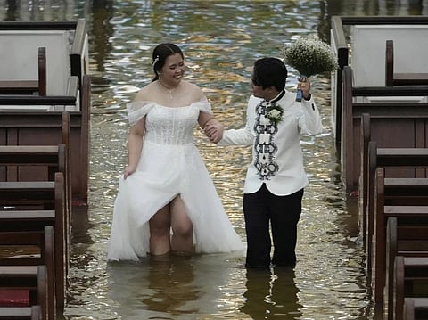 Newlyweds Jade Rick Verdillo right, and Jamaica walk hand in hand during their wedding at the flooded Barasoain church in Malolos, Bulacan province, Philippines on Tuesday, July 22, 2025. 

