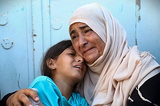 A woman and a child react after identifying the body of a family member at the Nasser hospital, among Palestinians killed in Israeli strikes on the al-Mawasi refugee camp and the eastern neighbourhoods of Khan Yunis in the southern Gaza Strip, on July 24, 2025.