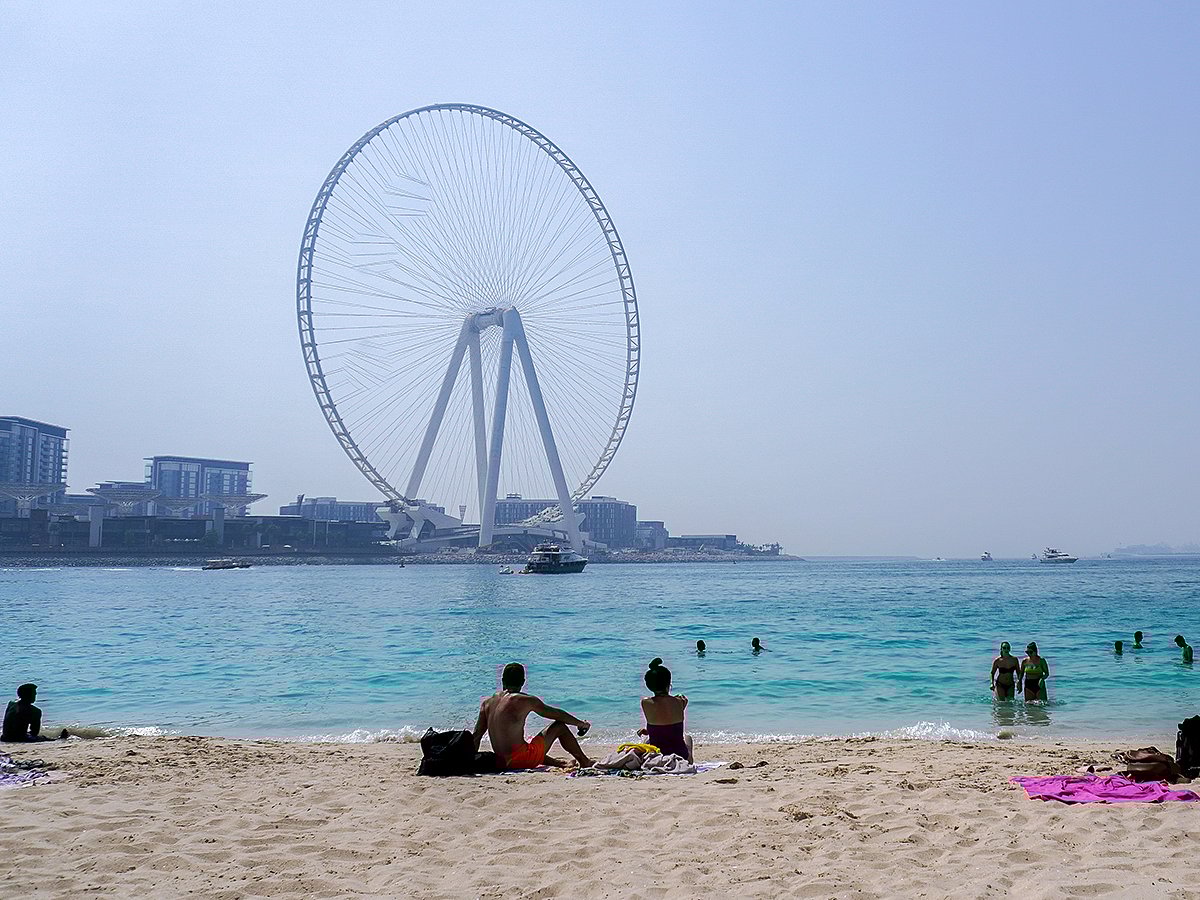 People sunbathe along the Marina beach near the Ain Dubai Ferris wheel.