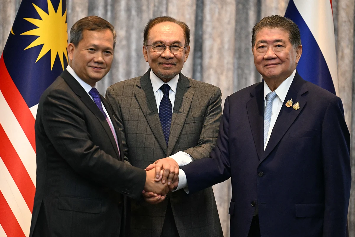 Malaysia's Prime Minister Anwar Ibrahim (C), Cambodia's Prime Minister Hun Manet (L) and Thailand's acting Prime Minister Phumtham Wechayachai (R) pose for photos as they shake hands following a press conference after talks on a possible ceasefire between Thailand and Cambodia in Putrajaya on July 28, 2025.