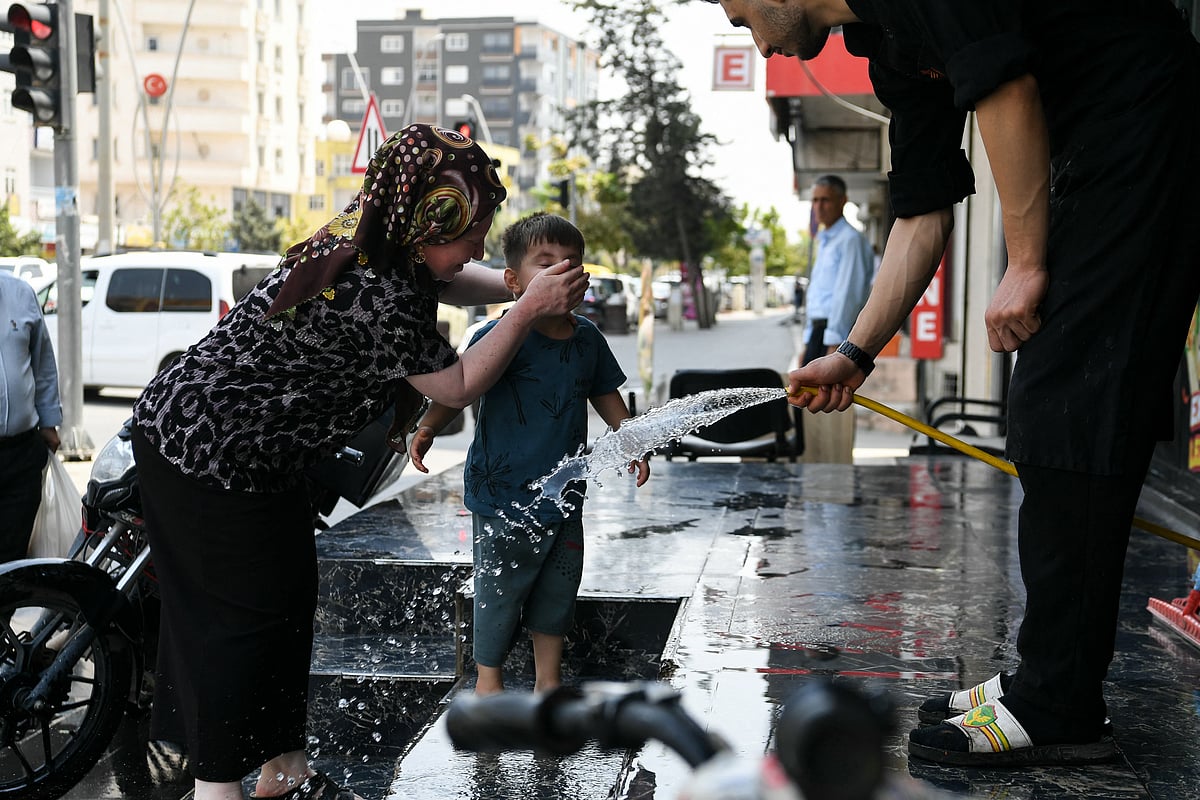 A woman puts water of the face of her child during an extreme heatwave at Silopi district in Sirnak on July 30, 2025.