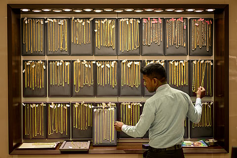 A salesman arranges gold chains at a jewellery store on July 5, 2025.