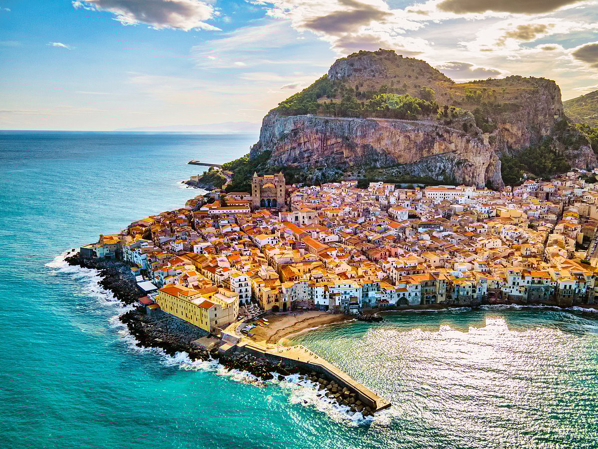 A drone view from above at the old town of Cefalu at sunset, medieval village of Sicily island, Province of Palermo, Italy. Europe. Cathedral of Cefalu