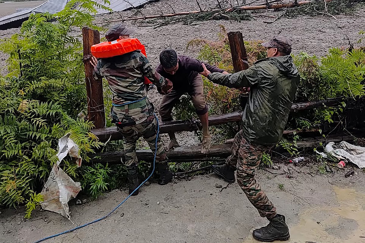 This handout photograph taken on August 5, 2025 and released by the Indian Army shows security personnel rescuing a local resident (C) from dense sludge during a search and rescue operation after a cloudburst caused a massive mudslide in India's Uttarakhand state.