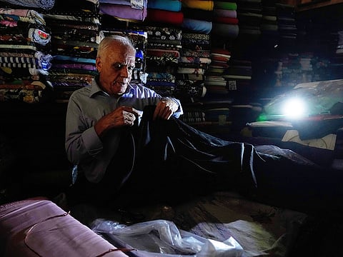 A textile seller works at his shop during power outage in Tehran, Iran, Tuesday, Aug. 5, 2025.