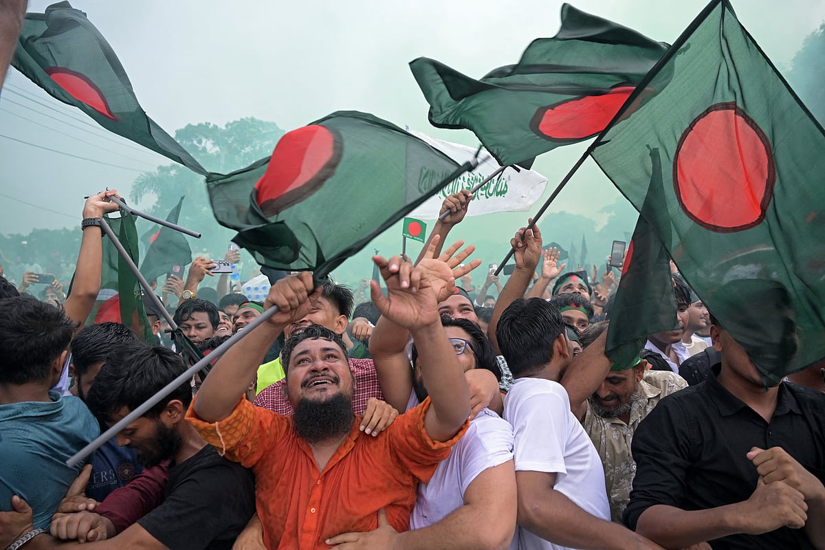 People hold Bangladesh's national flag as they celebrate during a government-organised event in Dhaka on August 5, 2025.