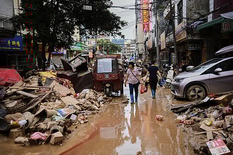 In this photo released by Xinhua News Agency, residents wade through debris along a flood-hit street after waters from a river overwhelmed towns following days of heavy rain, in Huaiji County, south China's Guangdong Province on June 19, 2025. 