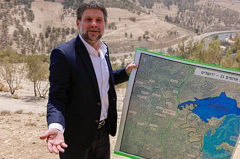 Israeli far-right Finance Minister Bezalel Smotrich holds a map of an area near the settlement of Maale Adumim, a land corridor known as E1, outside Jerusalem in the occupied West Bank, on August 14, 2025, after a press conference at the site.