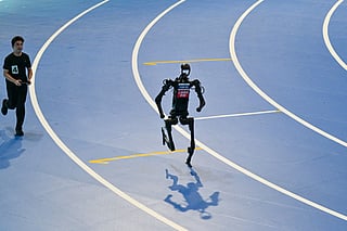 An engineer (L) controls a robot as it competes in the 400M run during the World Humanoid Robot Games in Beijing on Friday.