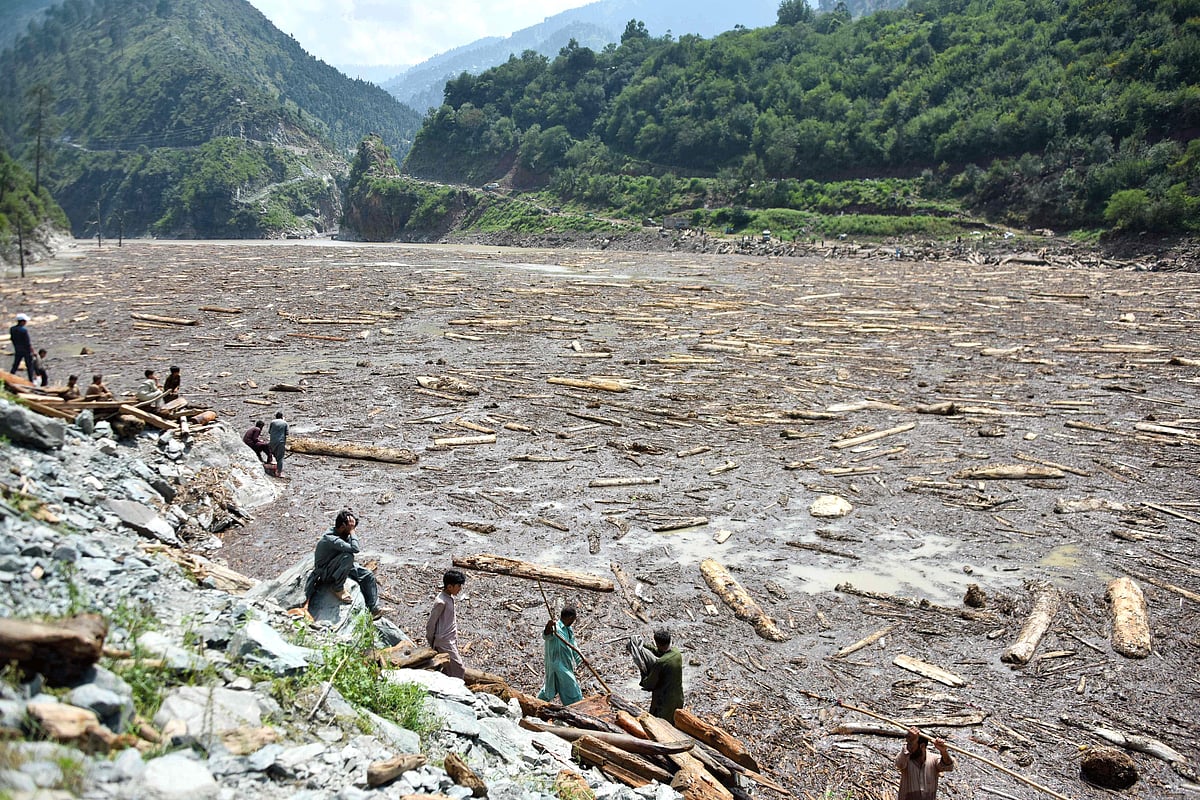 Locals collect woods from Noseri Dam near Muzaffarabad, the capital of Pakistan-administered Kashmir, on August 16, 2025, a day after flash floods.  
