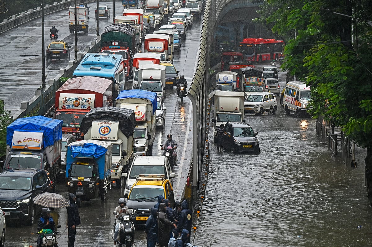 Vehicles make their way through a flooded road during heavy rain in Mumbai on August 19, 2025.
