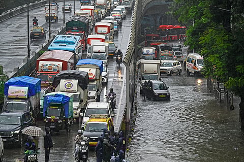 Vehicles make their way through a flooded road during heavy rain in Mumbai on August 19, 2025.