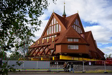 People look at the Kiruna Church, a Sami style wooden Swedish Lutheran church, called Kiruna Kyrka in Swedish, in Kiruna, Sweden, Monday, Aug. 18, 2025, a day before it will be moved along a 5-kilometre route east to a new city centre as part of the town's relocation. 