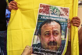 A protester lifts flags bearing a portrait of leading member of the Fatah party Marwan Barghouti, the most high-profile Palestinian detainee in Israeli custody, during a march supporting him in Ramallah city in the occupied West Bank on August 19, 2025.