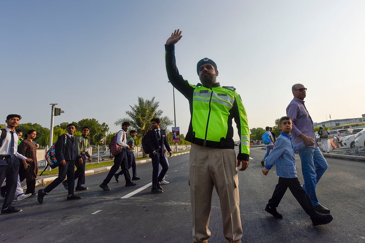 Sharjah police officers help students and parents cross the road on the first day of school after summer vacation at Muweilah school area in Sharjah.