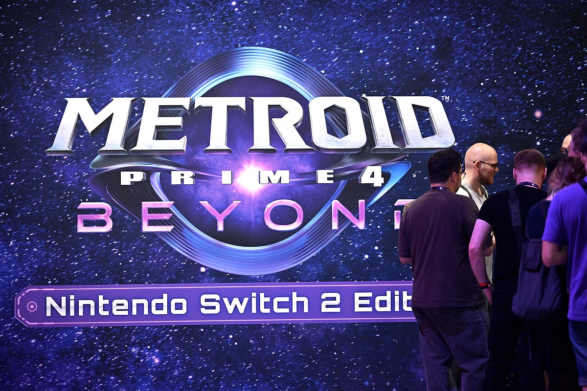 Visitors walk past a placard of the Metroid Prime 4: Beyond – Nintendo Switch 2 Edition video game at the Ninentdo booth during the Gamescom video games trade fair at the Trade Fair Center in Cologne, western Germany, on the first day of the fair on August 20, 2025.