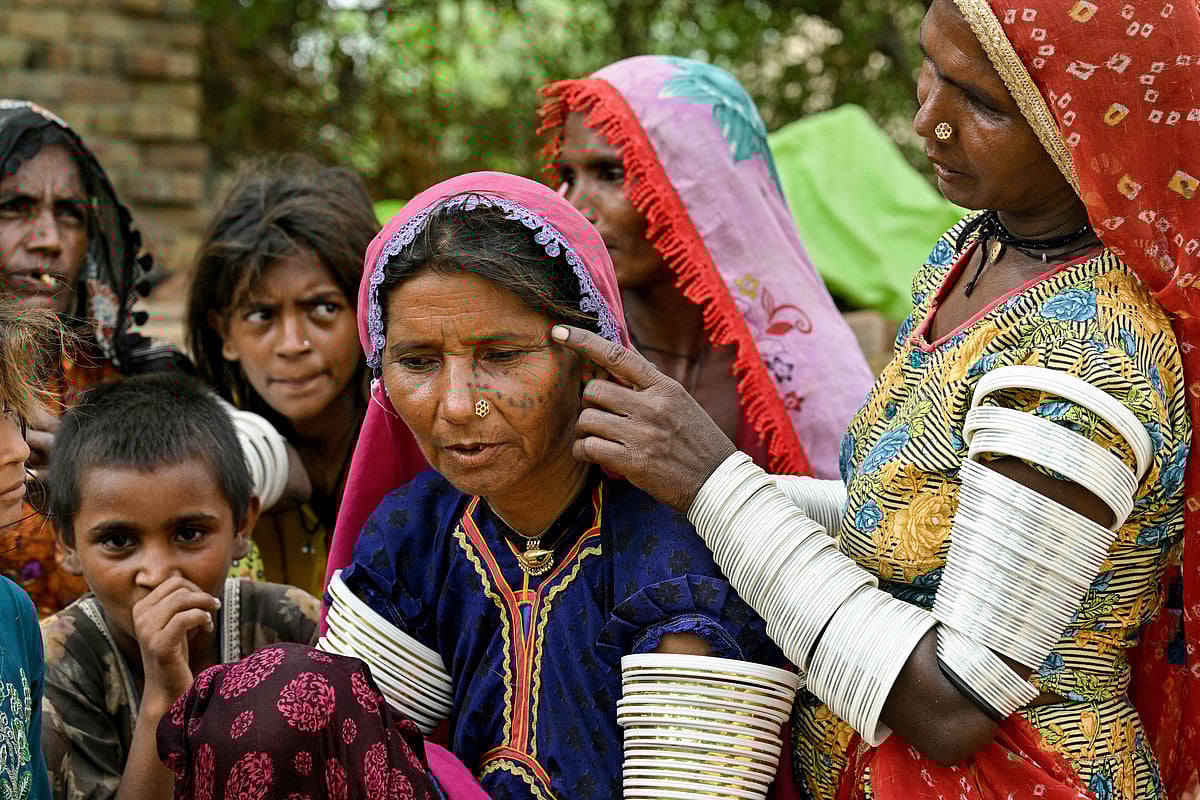 A villager in traditional attire pointing to an indigenous tattoo inked on Reshma's  face at the Ponjo Kolhi village, about 30 km from Umerkot, a Hindu-majority district in Pakistan. In rural Sindh province, Pakistan, the centuries-old tradition of tattooing young Hindu girls’ faces, hands, and arms is slowly fading. 