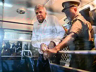 Sri Lanka's former president Ranil Wickremesinghe is escorted to his seat in a prison bus in Colombo on August 22, 2025, after a magistrate ordered him to be held in remand custody till August 26, 2025, following allegations that he misused state funds to travel to Britain in 2023. 