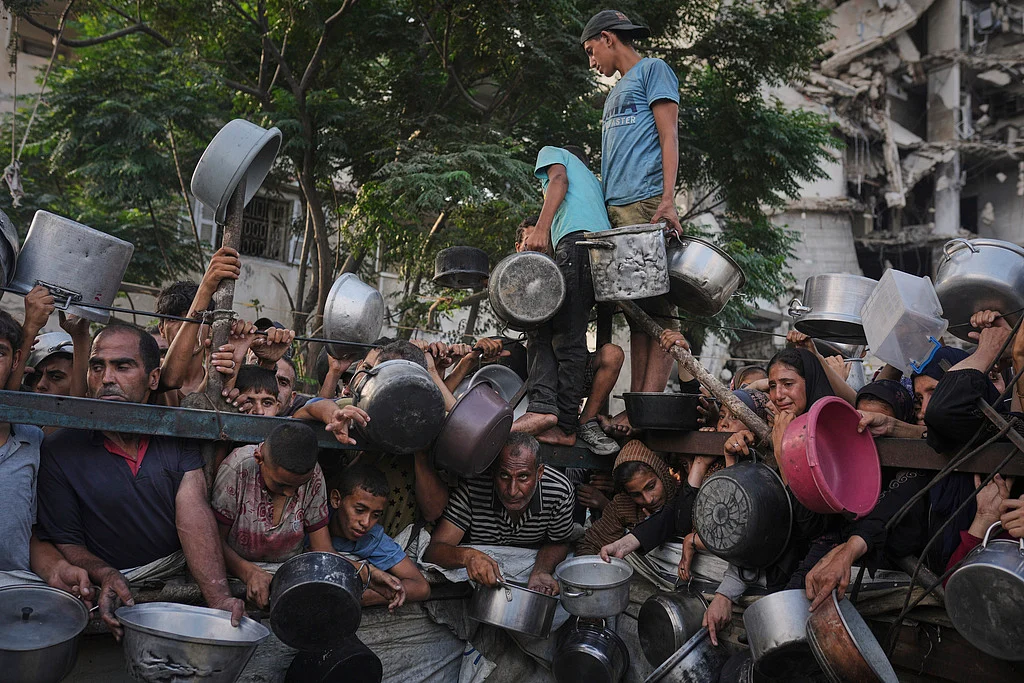 Palestinians struggle to get donated food at a community kitchen in Gaza City, northern Gaza Strip, July 14, 2025. 