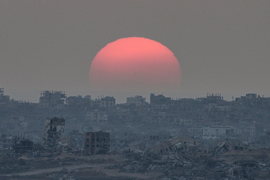 The sun sets behind buildings destroyed during Israeli ground and air operations in the Gaza Strip, as seen from southern Israel, Tuesday, August 26, 2025. 