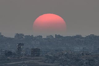 The sun sets behind buildings destroyed during Israeli ground and air operations in the Gaza Strip, as seen from southern Israel, Tuesday, August 26, 2025. 