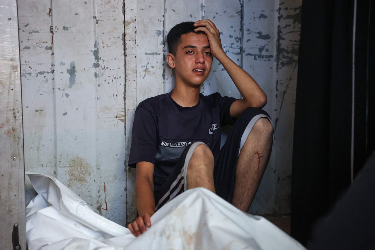 A Palestinian youth mourns by the body of a relative killed in Israeli strikes on Gaza City at dawn, at the Al-Shifa hospital on September 2, 2025.  