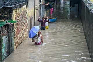 People walk through a waterlogged area as the river Yamuna crosses the danger mark following incessant rainfall, at Yamuna Bazar in New Delhi on Tuesday.  
